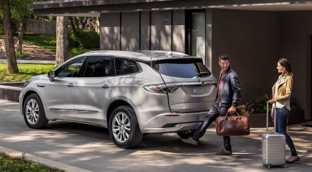 Person loading luggage in a grey 2022 Buick Enclave Avenir