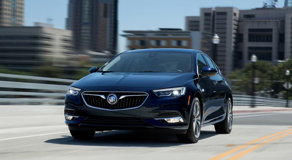 Black 2020 Buick Regal Sportback driving over a city bridge.