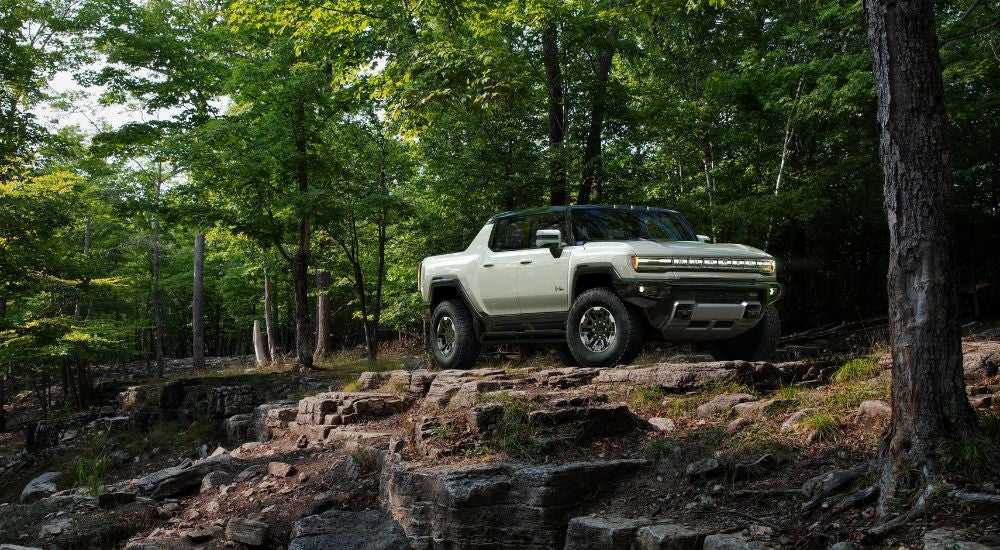 White 2023 GMC Hummer EV driving through the woods.