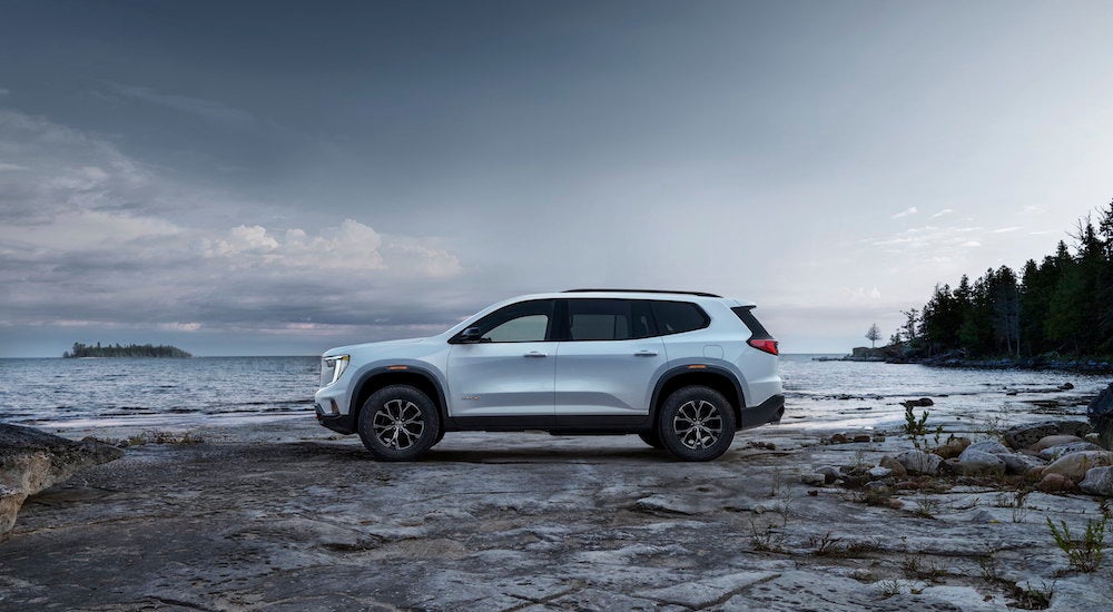 A white 2025 GMC Acadia AT4 is shown from the side.