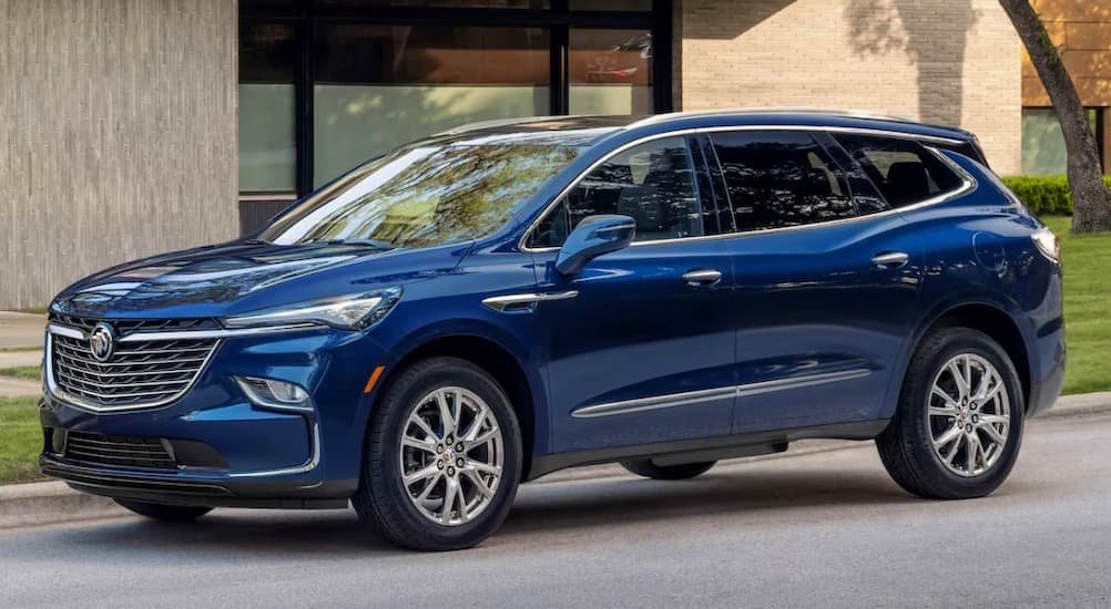 A blue 2023 Buick Enclave parked near a house.