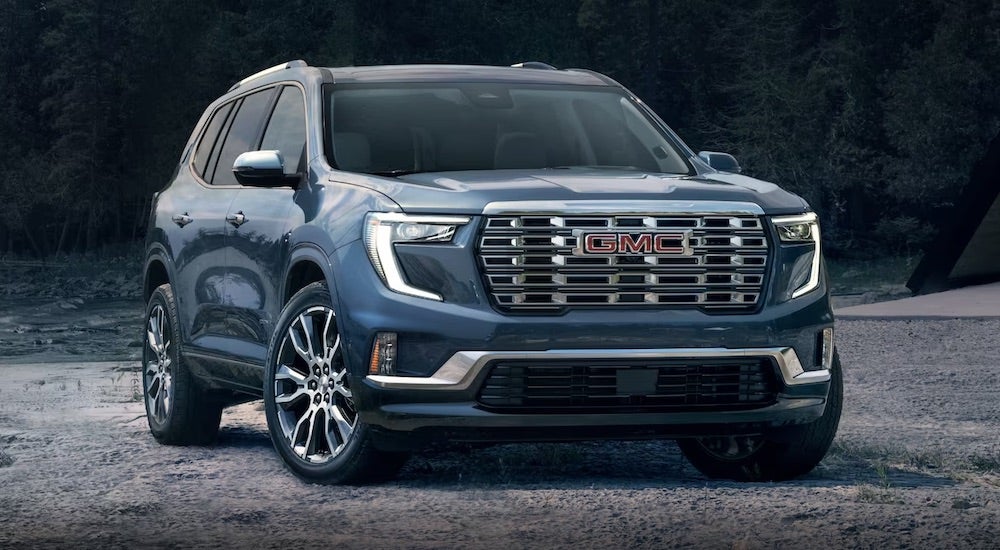 A blue 2024 GMC Acadia Denali is shown parked on a beach.