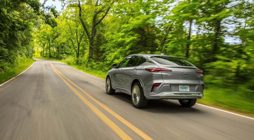 A rear view of a grey 2024 Buick Envista Avenir driving down a road.
