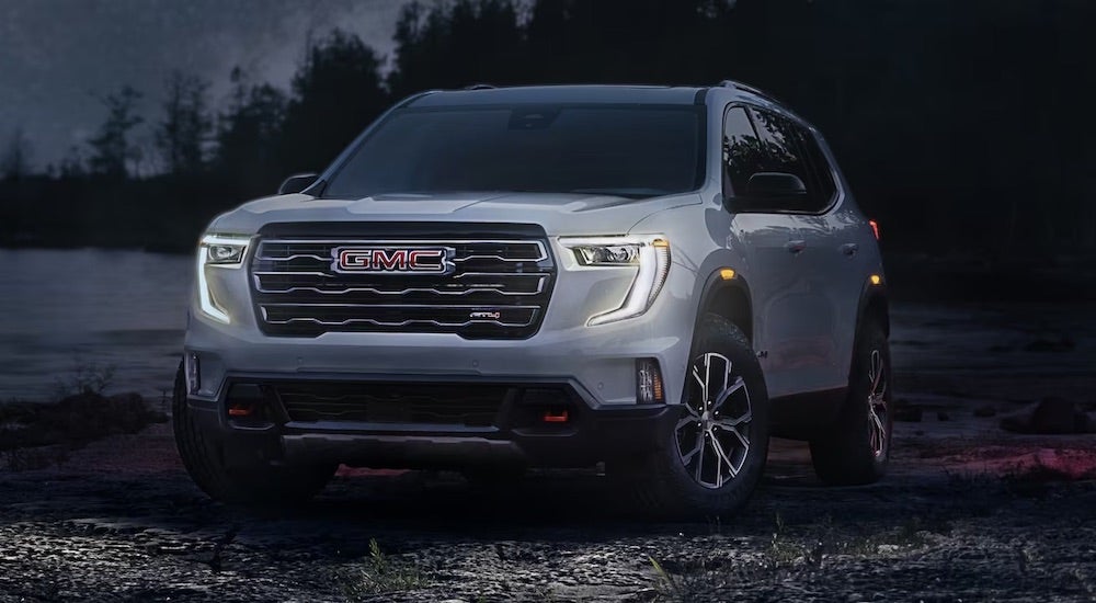 A white 2024 GMC Acadia Denali is shown parked off-road after visiting a GMC dealer.
