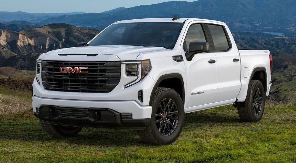 A white 2024 GMC Sierra 1500 Pro Graphite Edition parked on a grassy mountain field.