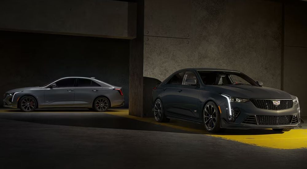 A silver 2026 Cadillac CT4-V and a grey CT4-V Blackwing parked in a parking garage.