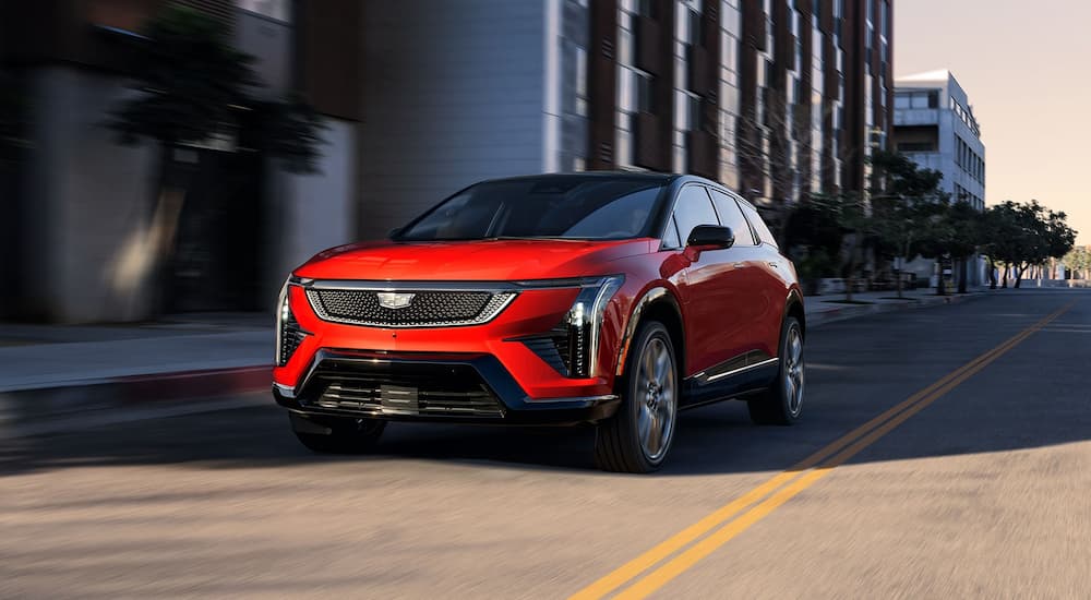 Red 2026 Cadillac OPTIQ-V driving from a Cadillac dealer near Ann Arbor.