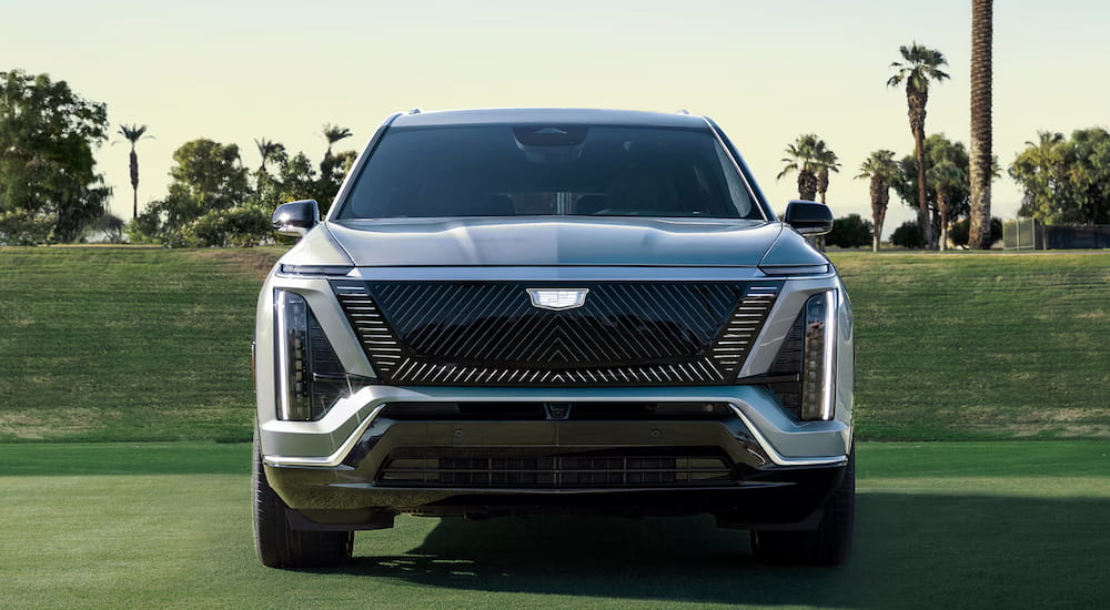 Front of a silver 2027 Cadillac VISTIQ parked on grass.