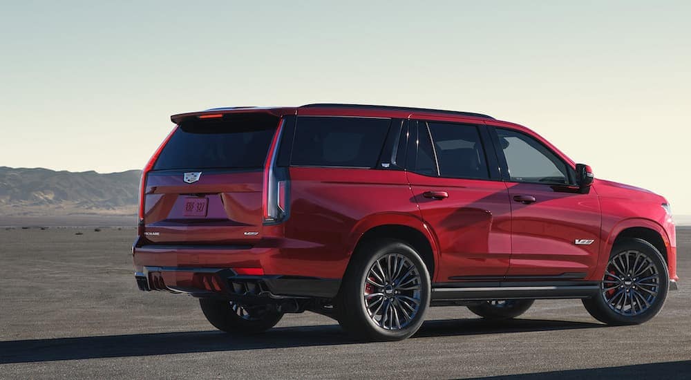 Rear angle view of a red 2024 Cadillac Escalade IQ parked off-road.