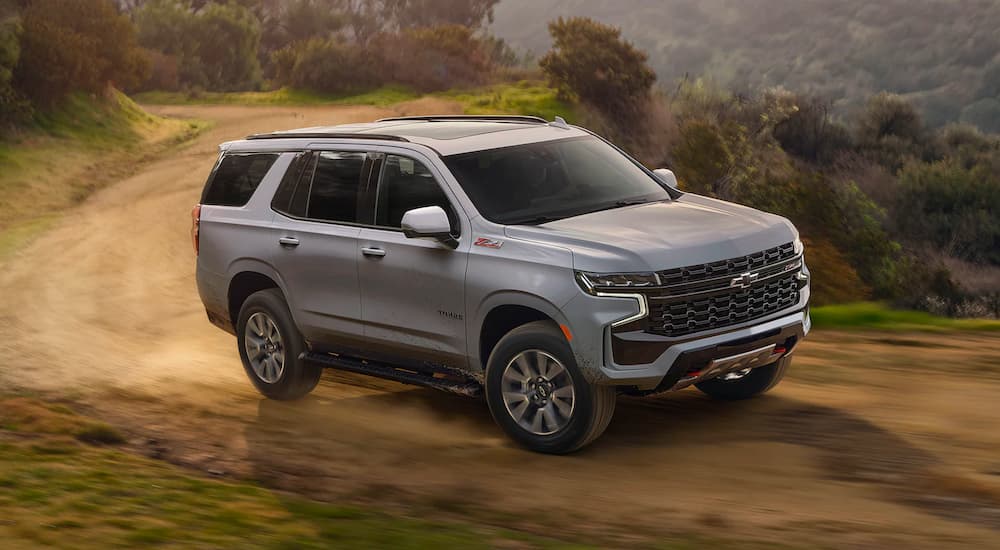 A grey 2025 Chevy Tahoe Z71 driving around a bend on a dirt trail.