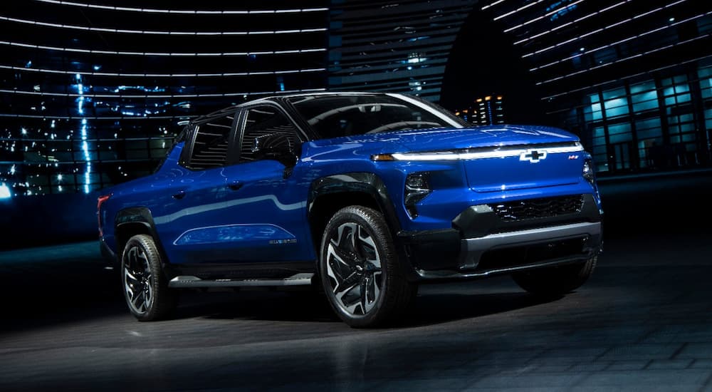 A blue 2024 Chevy Silverado EV RST parked in the showroom of a Chevy dealer near Canton.