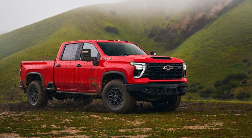 A red 2024 Chevy Silverado 3500HD is shown parked off-road in a grass valley.
