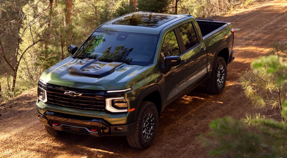 Green 2027 Chevy Silverado 1500 driving on a dirt road.