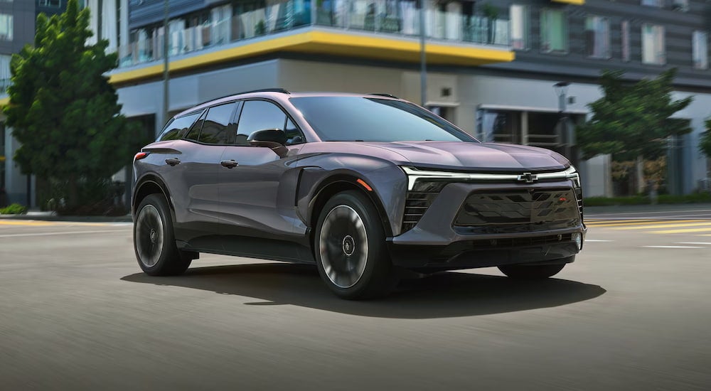 A grey 2025 Chevy Blazer EV driving through an intersection.