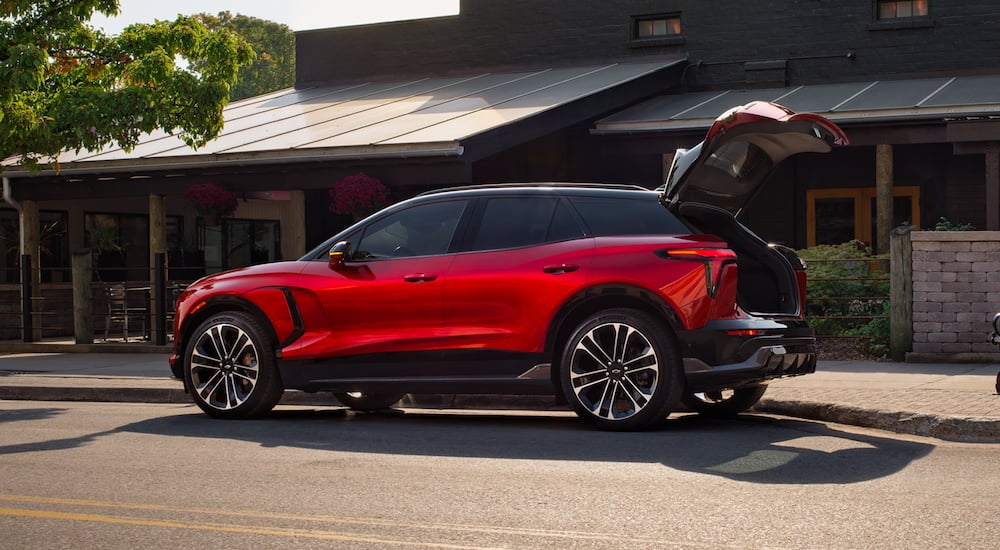 Side angle of a red 2025 Chevy Blazer EV for sale with an open hatchback.