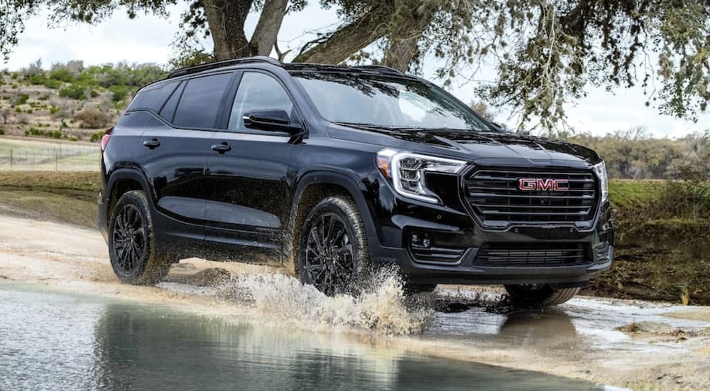 A black 2024 GMC Terrain is shown driving.