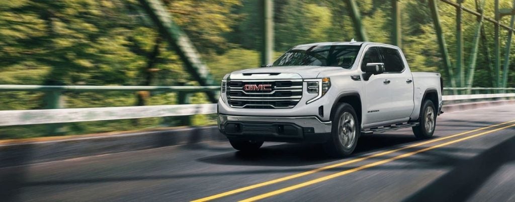 A white 2022 GMC Sierra 1500 driving over a bridge from a used GMC dealer.