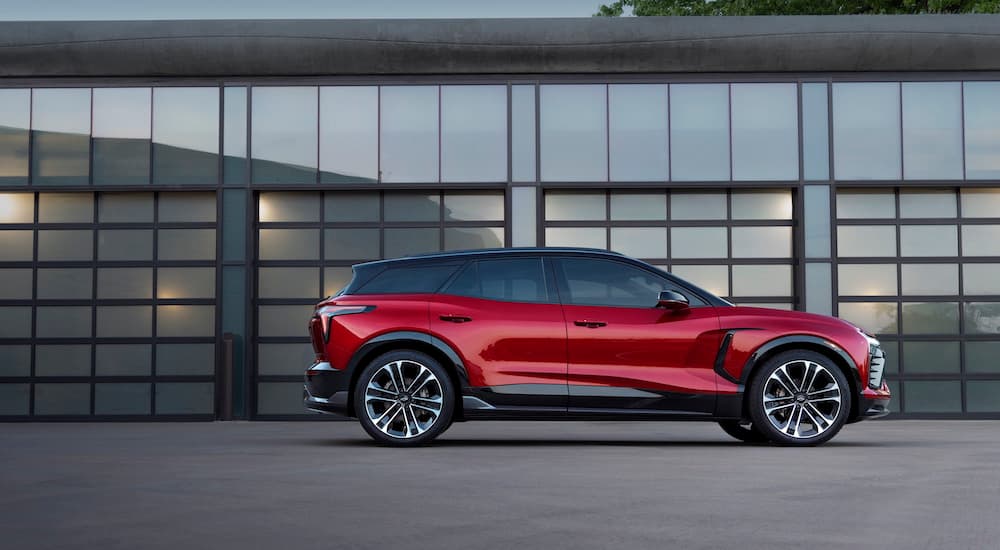 A side angle view of a red 2024 Chevy Blazer EV SS parked outside a building.