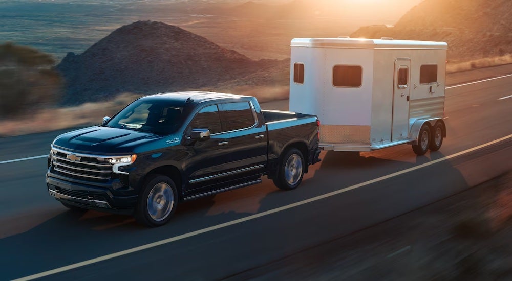 A black 2024 Chevy Silverado 1500 ZR2 towing a trailer.