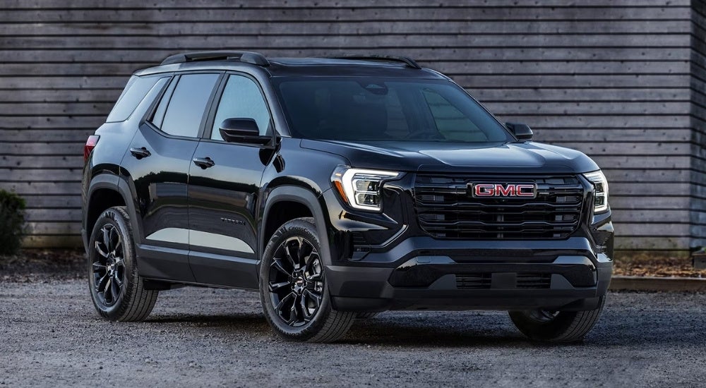 A black 2025 GMC Terrain Elevation parked in front of a wood building.