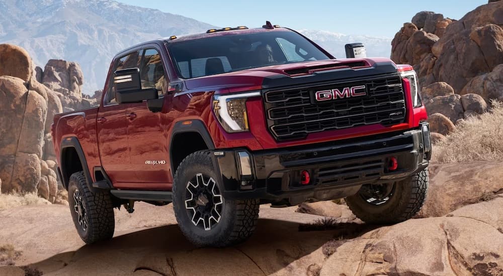 A red 2024 GMC Sierra 2500 HD driving off-road.