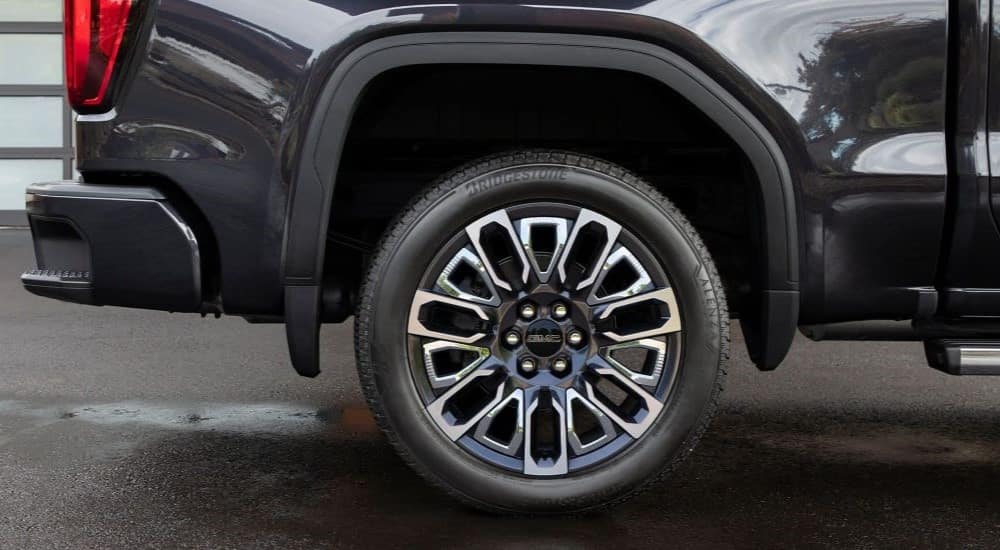 A close up shows the wheel on a dark grey 2024 GMC Sierra 1500.