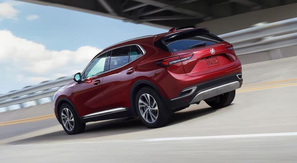 A red 2023 Buick Envision driving on a highway to visit a Buick dealer.