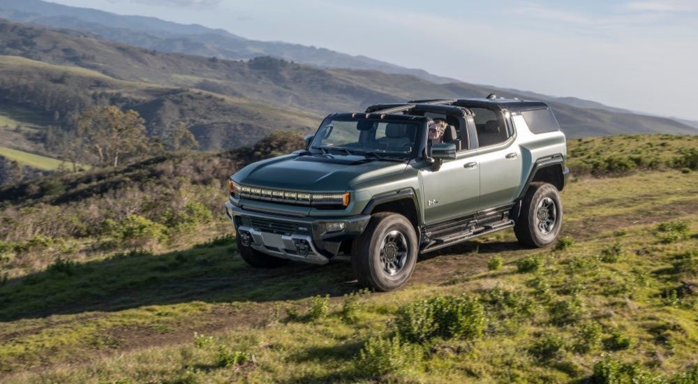 A grey 2024 GMC Hummer EV parked off-road on a grassy hill after visiting a GMC dealer near Detroit.