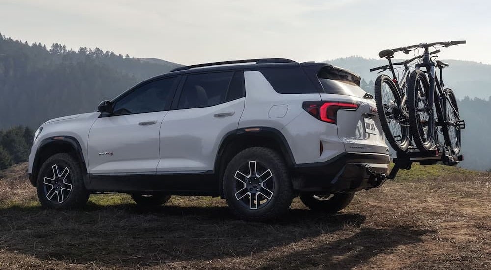 Rear of a white 2027 GMC Terrain parked on a grassy hill.