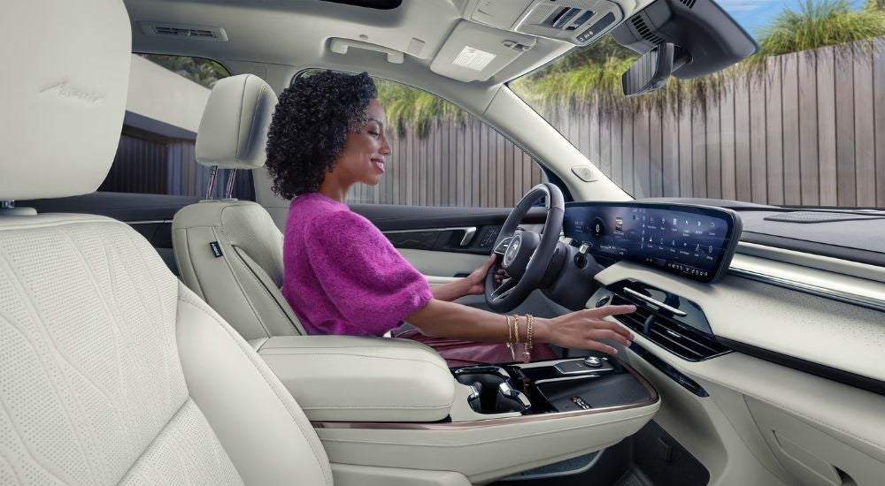 A woman sitting in a 2027 Buick Enclave Avenir with a white interior.