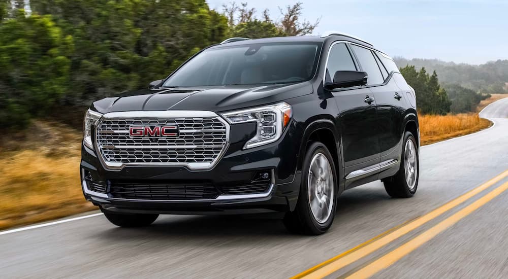 A black 2023 GMC Terrain Denali driving on a highway.
