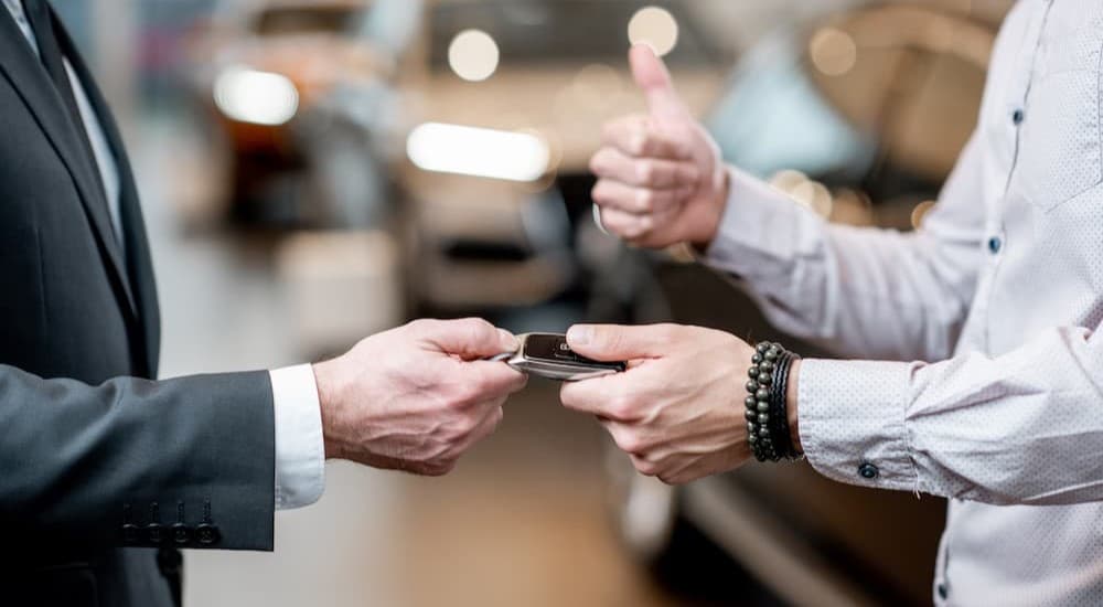A person handing over a key fob to another person.