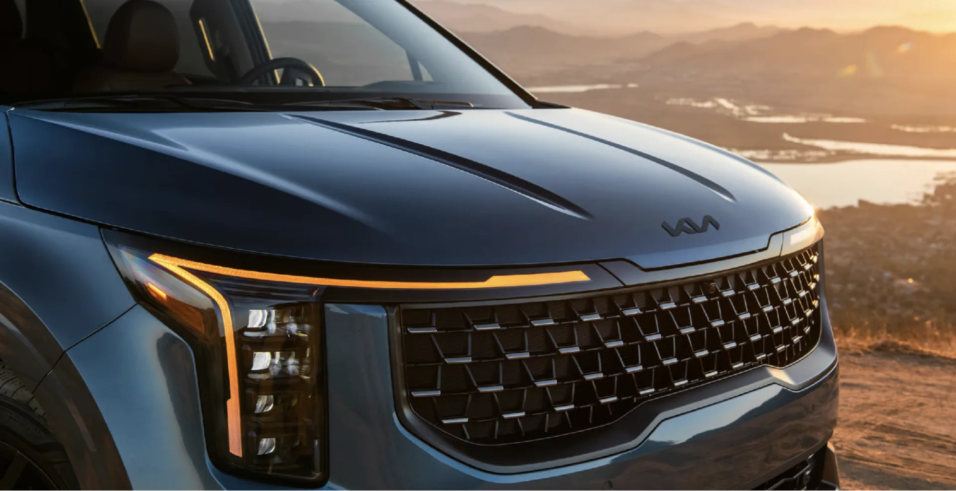 Vertical LED headlights with distinct amber DRLs shown on the 2027 Kia Carnival Hybrid SX Prestige in Astra Blue