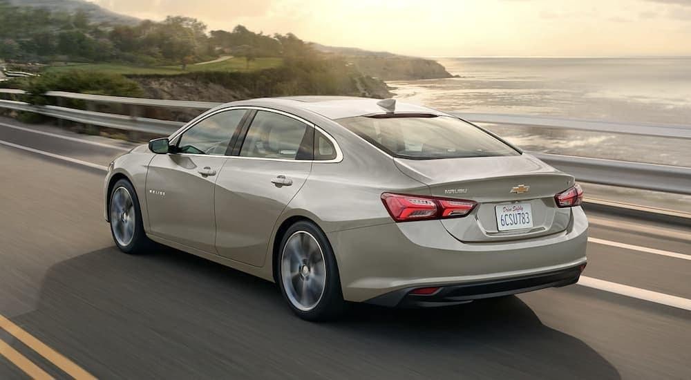 After viewing cheap used cars near Dayton, a beige 2023 Chevy Malibu, is shown driving on a bridge.