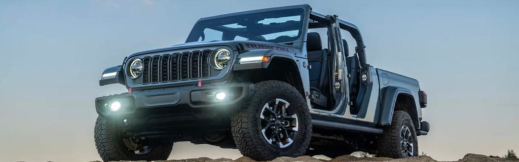 Jeep Wrangler Rubicon with open doors parked on rocky terrain.