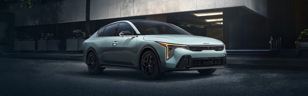 2025 Kia K4 fastback sedan parked outside a modern building at dusk