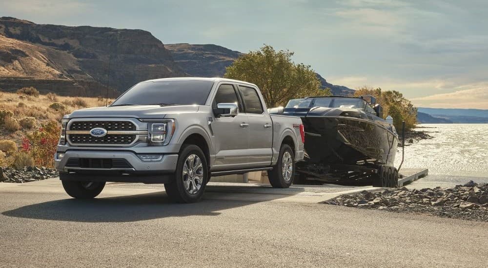 A silver 2023 Ford F-150 towing a boat.