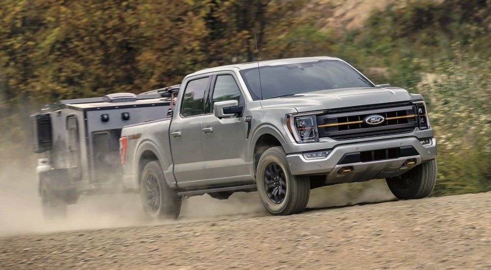 A silver used 2023 Ford F-150 Tremor towing a trailer behind