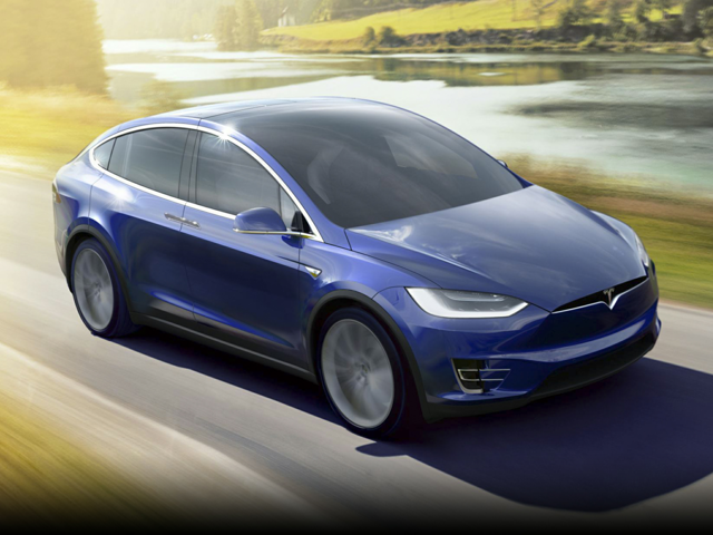 A blue 202 Tesla Model X driving down a street