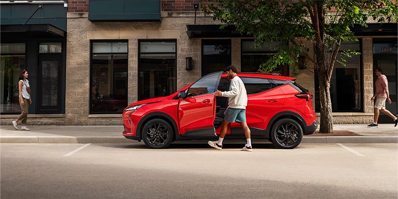 A red Chevrolet Bolt electric vehicle parked on a city street.