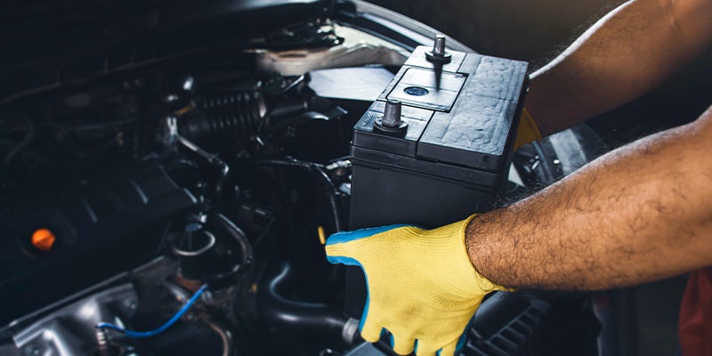 Close-up of a service technician replacing a vehicle's battery.
