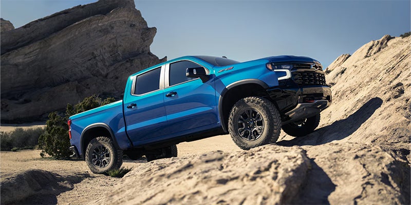A blue Chevrolet Silverado 1500 driving off-road.