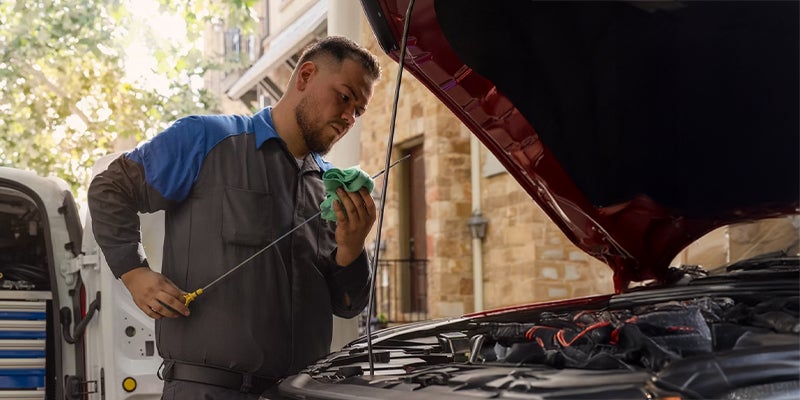 A service technician doing an inspection of the oil levels of a vehicle in the service center.