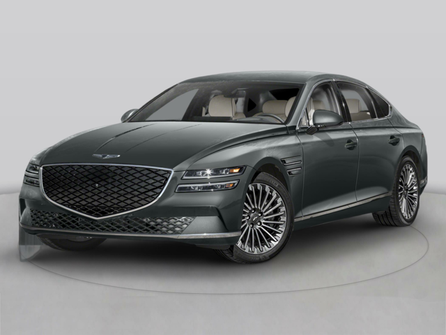 An all-new silver 2025 Genesis Electrified G80 parked in front of a gray backdrop. - Genesis of Baton Rouge, LA
