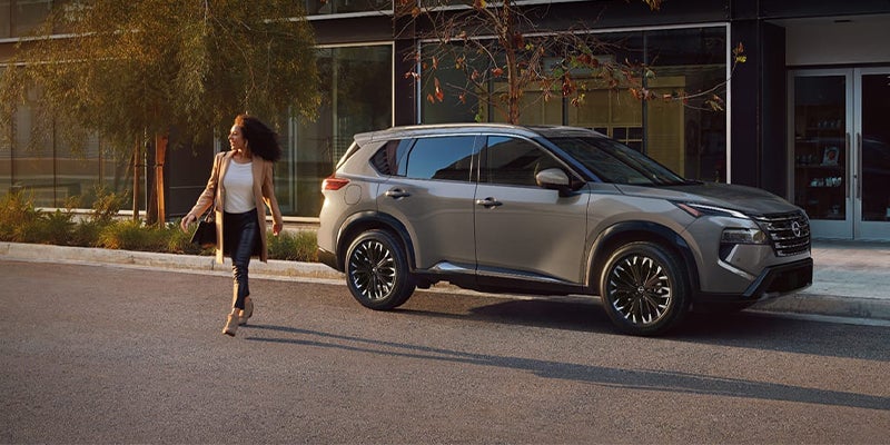 The driver walking away from their silver Nissan Rogue parked on a city street.