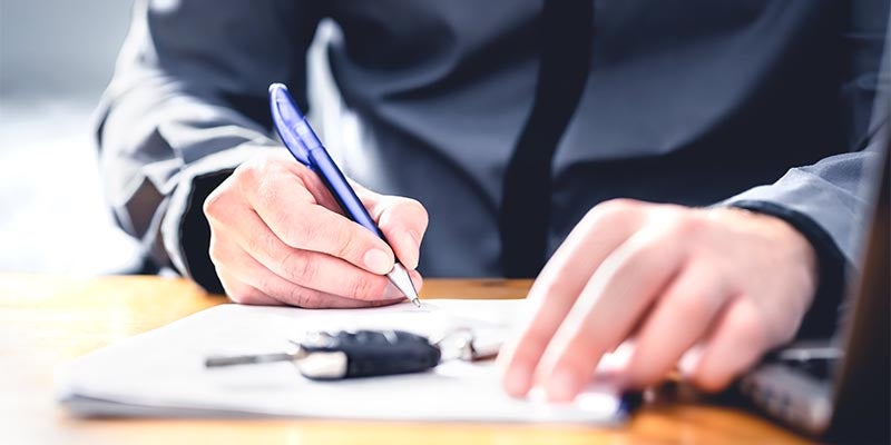 Signing paperwork with keys on the table.