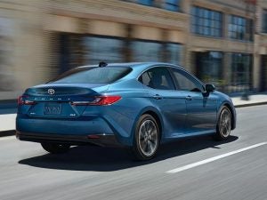 The back of the 2026 Toyota Camry Hybrid driving through the city.