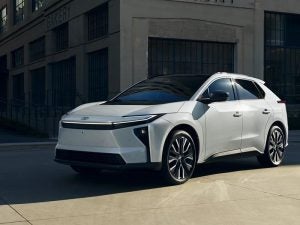 A white 2026 Toyota bZ Electric SUV parked near a building.