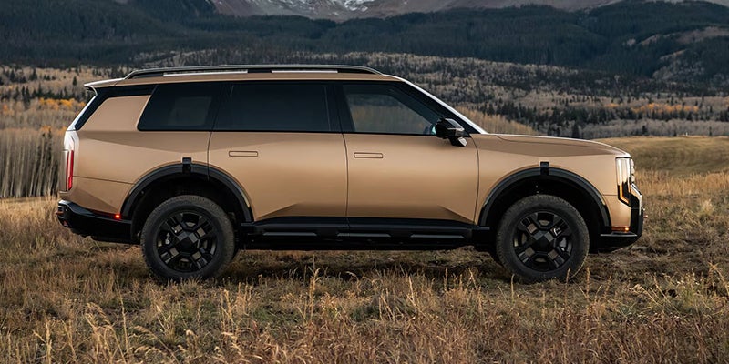 A Kia Telluride in Terrain Brown Matte paint parked in a field.