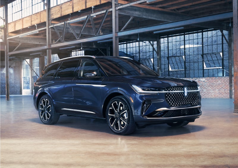 2024 navy blue Lincoln Nautilus parked in a well lit brick warehouse. Large windows are in the foreground. 